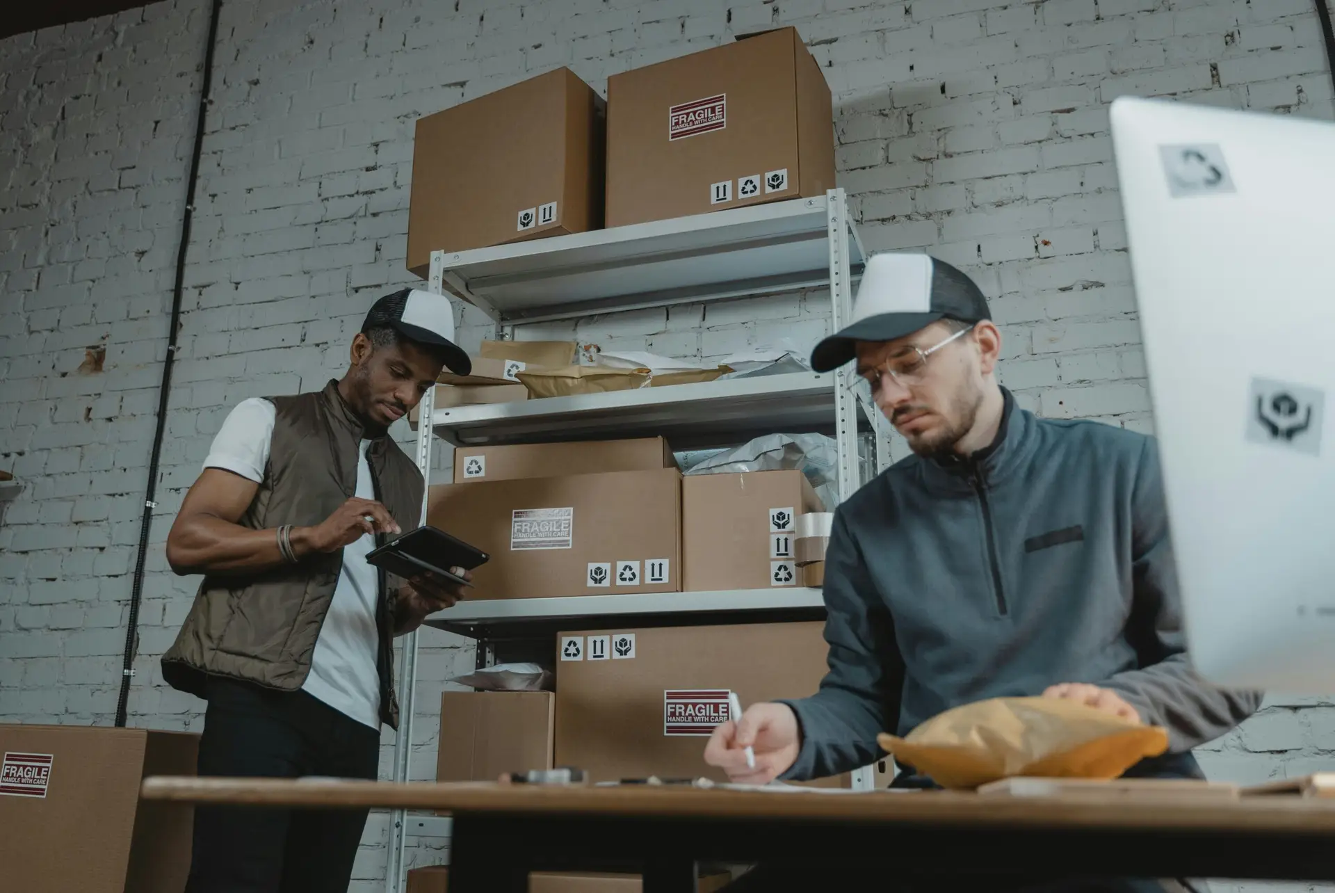 Two warehouse employees organizing and packing parcels for delivery in a modern indoor setting.